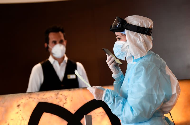 A doctor in protective suit makes a phone call in the hall of a hotel where people suffering from the coronavirus disease (COVID-19) are quarantined, in Bergamo