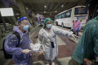 A public health worker guides Chinese tourists from Shanghai who arrived at Suvarnabhumi airport on special tourist visas, in Bangkok, Thailand, Tuesday, Oct. 20, 2020. Thailand on Tuesday took a modest step toward reviving its coronavirus-battered tourist industry by welcoming 39 visitors who flew in from Shanghai, the first such arrival since normal traveler arrivals were banned almost seven months ago. (AP Photo/Wason Wanichakorn)
