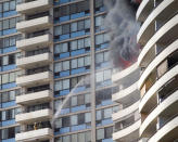 <p>Firefighters on a lower balcony spray water upwards while trying to contain a fire at the Marco Polo apartments, Friday, July 14, 2017, in Honolulu, Hawaii. (Photo: Marco Garcia/AP) </p>