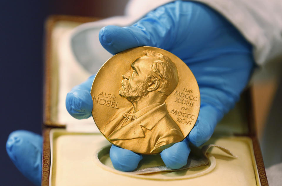 FILE - In this April 17, 2015, file photo, a national library employee shows a gold Nobel Prize medal in Bogota, Colombia. The Nobels, with new winners announced starting Monday, Oct. 5, 2020, often concentrate on unheralded, methodical, basic science. (AP Photo/Fernando Vergara, File)