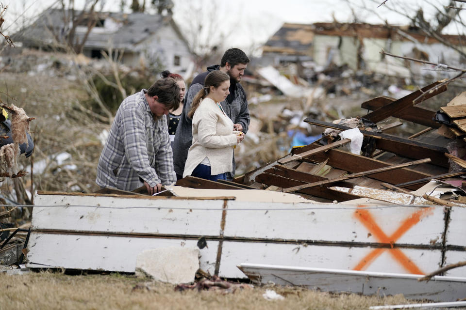 FILE -Brandon Clark, behind, injured from the tornado, returns to his destroyed home for the first time with Laura Shepherd, Tyler Shepherd, left, and his wife Georgialee Clark, behind in the aftermath of tornadoes that tore through the region, in Dawson Springs, Ky., Wednesday, Dec. 15, 2021. One year ago Saturday, Dec. 10, 2022, a massive tornado obliterated wide swaths of Dawson Springs, Ky. (AP Photo/Gerald Herbert, File)