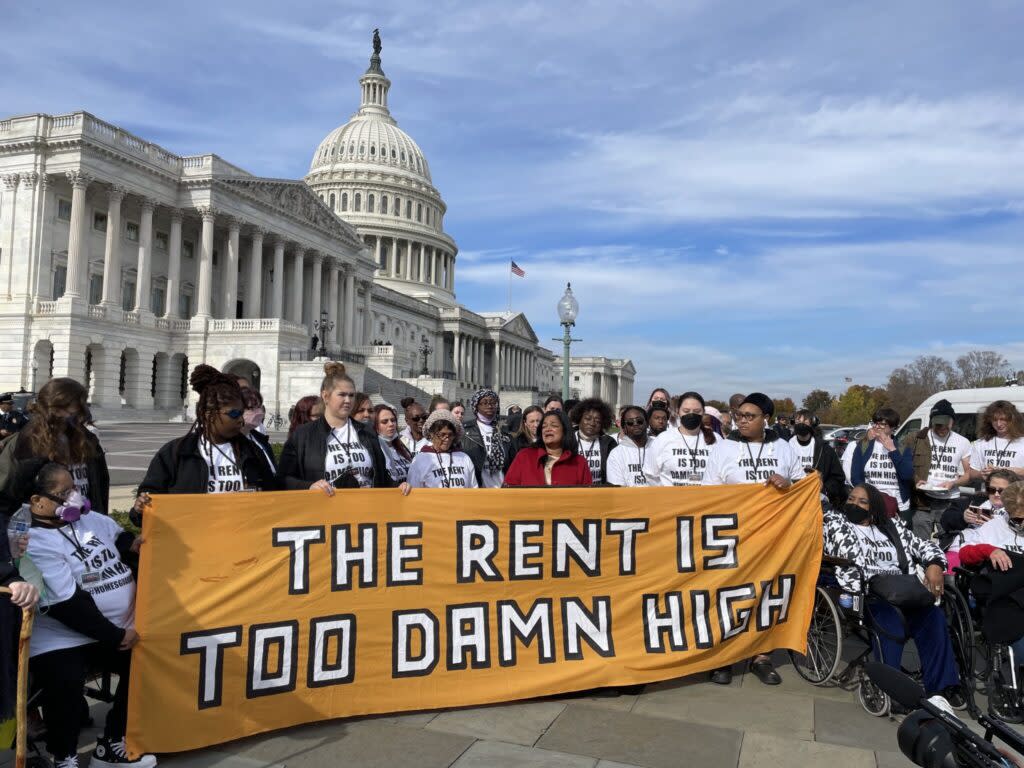tenant advocates at a rally outside the U.S. capitol hold a banner that reads: THE RENT IS TOO DAMN HIGH"