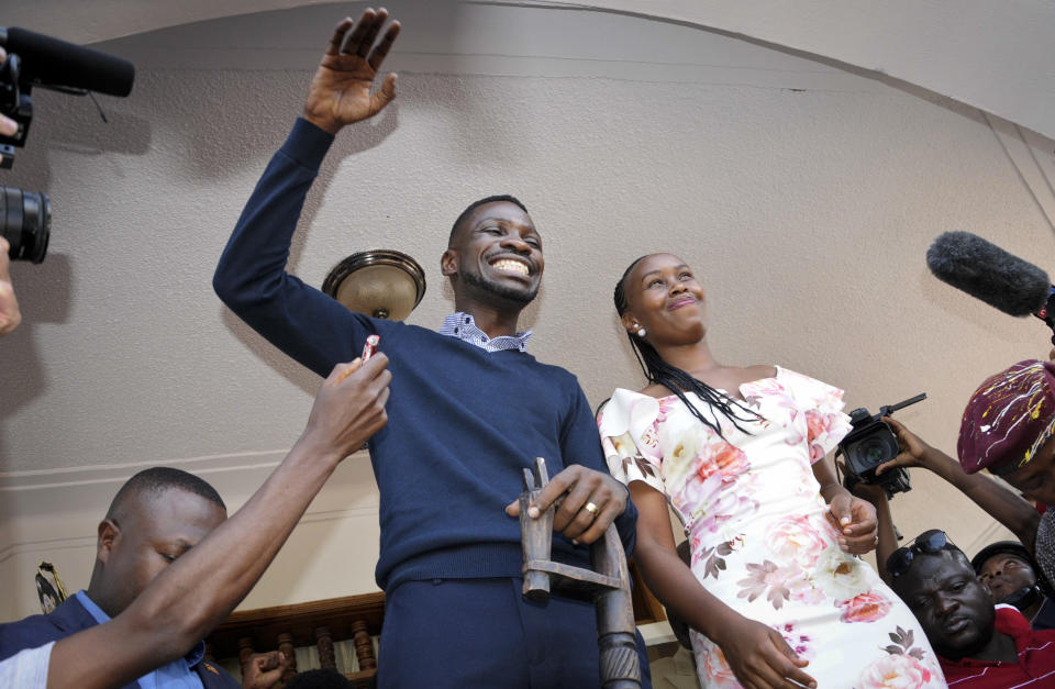 Pop star-turned-opposition lawmaker Bobi Wine, whose real name is Kyagulanyi Ssentamu, waves to supporters accompanied by his wife Barbara Itungo Kyagulanyi at his home in Kampala, Uganda Thursday, Sept. 20, 2018. Wine vowed Thursday to continue his fight for more freedom in the country "or we shall die trying," shortly after security forces took him into custody on his arrival from the United States after treatment for alleged torture. (AP Photo/Ronald Kabuubi)