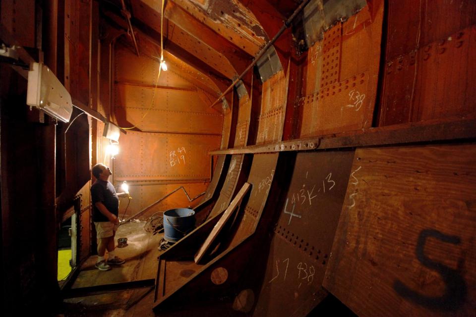 FILE- In this Aug. 30, 2010, file photo, Jesse Lebovics, longtime caretaker of USS Olympia, illuminates a coal bunker showing interim repairs at and below the waterline of the ship, in Philadelphia. The USS Olympia, a one-of-a-kind steel cruiser from the Spanish-American War, has undergone extensive repairs that make it more stable than it has been in years. (AP Photo/Matt Rourke, File)