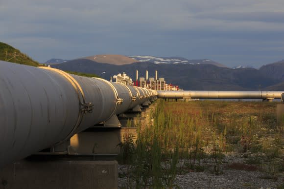 A pipeline with snow covered mountains in the background.
