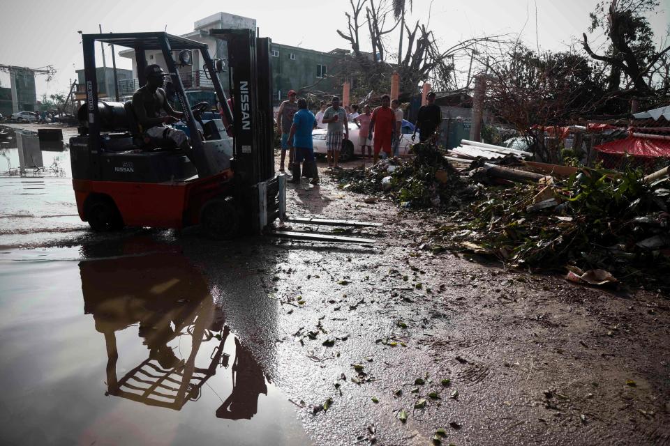 Julian Matadamas (C) removes debris left by the passage of Hurricane Otis in Puerto Marques, Guerrero State, Mexico, on October 28, 2023.