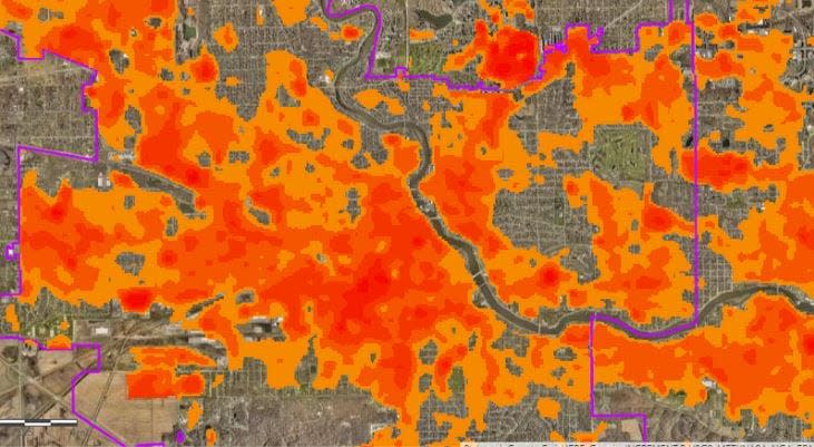 A heat map overlaid on an aerial view South Bend shows how areas of the city west of the St. Joseph River grow hotter than others on sunny days because of a sparser tree canopy.