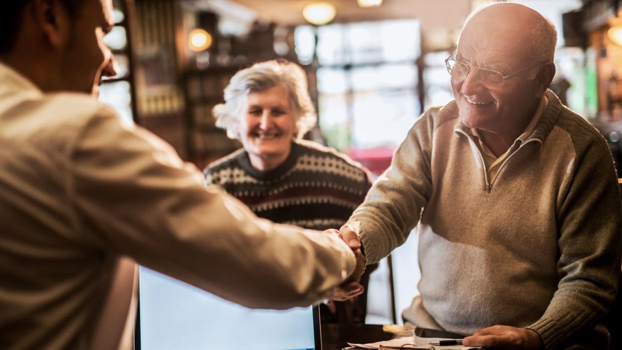 Smiling senior man shaking hands with financial advisor.