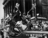 <p>Members of the Women's Royal Army Corps wave the Union Jack flag as they drive their service jeep through the streets of London. </p>