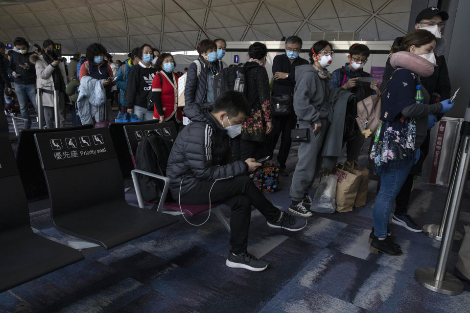 Masked passengers line up to board a flight for Beijing at the airport in Hong Kong on Sunday, Feb. 9, 2020. China's virus death toll rose above 800, passing the number of fatalities in the 2002-2003 SARS epidemic, but fewer new cases were reported in a possible sign its spread may be slowing as other nations step up efforts to block the disease (AP Photo/Ng Han Guan)