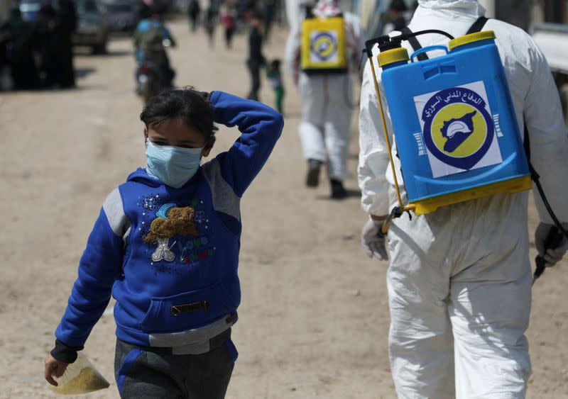 FILE PHOTO: An internally displaced Syrian girl wears a face mask as members of the Syrian Civil defence sanitize the Bab Al-Nour internally displaced persons camp, to prevent the spread of coronavirus disease (COVID-19) in Azaz