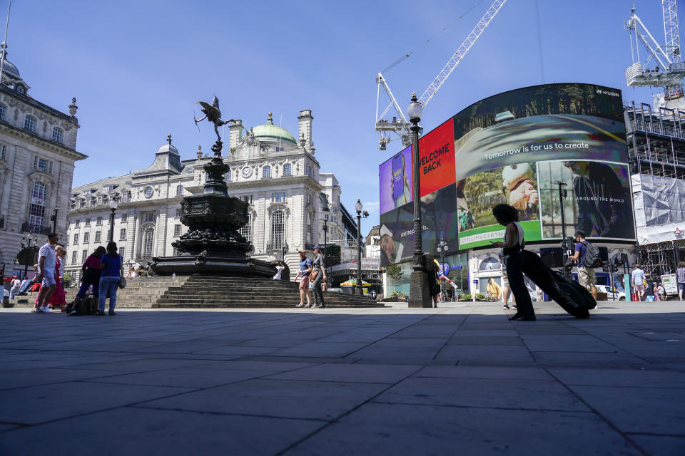 People walk in Piccadilly Circus, in London, Monday, June 14, 2021. British Prime Minister Boris Johnson is expected to confirm Monday that the next planned relaxation of coronavirus restrictions in England will be delayed as a result of the spread of the delta variant first identified in India. (AP Photo/Alberto Pezzali)