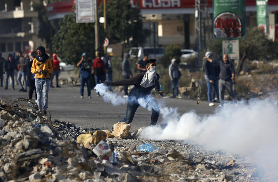 Palestinian demonstrator throws back tear gas fired by Israeli troops during the protest against the U.S. announcement that it no longer believes Israeli settlements violate international law., at checkpoint Beit El near the West Bank city of Ramallah, Tuesday, Nov. 26, 2019, (AP Photo/Majdi Mohammed)