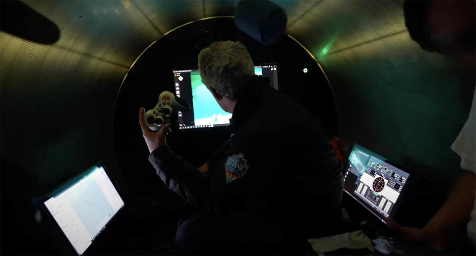 Stockton Rush sits inside the Titan submersible, holding up the gaming controller that operates the vessel.