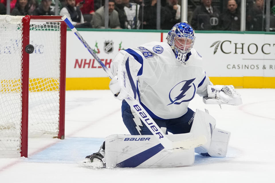 A shot by the Dallas Stars goes wide as Tampa Bay Lightning goaltender Andrei Vasilevskiy (88) defends his net during the first period of an NHL hockey game, Saturday, Dec. 2, 2023, in Dallas. (AP Photo/Julio Cortez)