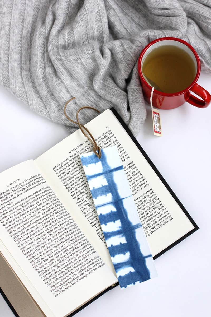 Blue and white DIY tie-dye bookmarks with leather tassels set on book pages