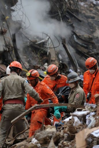 Rescuers carry the corpse of one of the victims of the building collapse in Rio de Janeiro