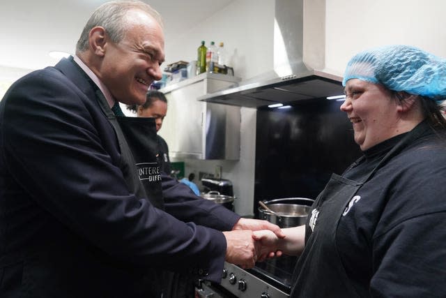 Liberal Democrats leader Sir Ed Davey shakes hands with a woman worker