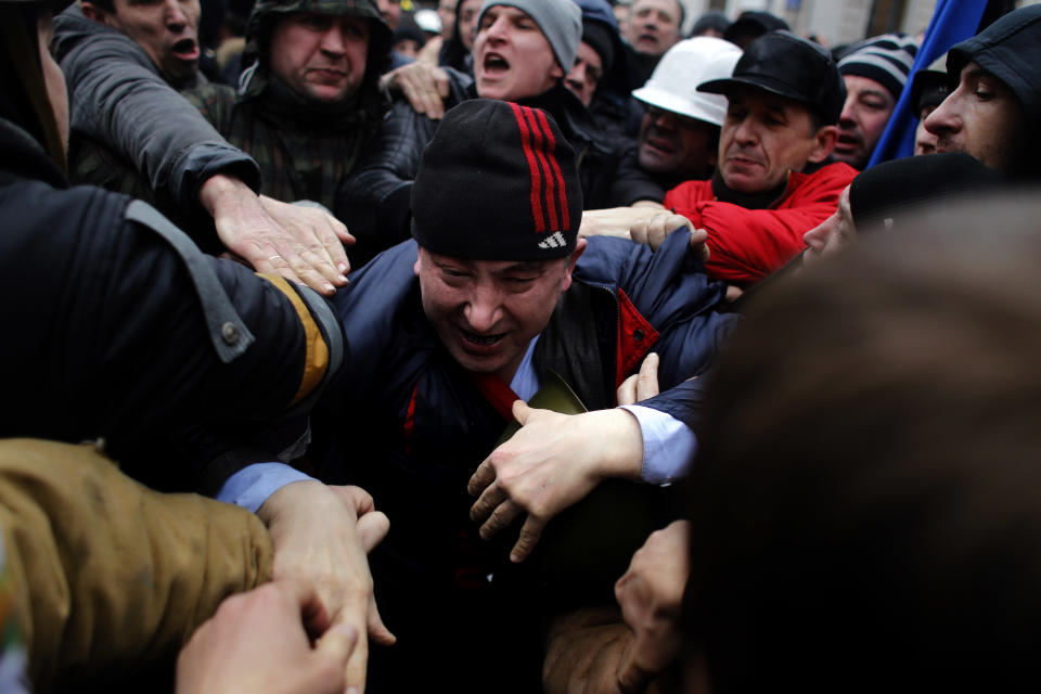 A suspected supporter of Ukraine's embattled president Viktor Yanukovych, center, is assaulted by anti-government protesters in Kiev, Ukraine, Saturday, Feb. 22, 2014. Fears that Ukraine could split in two mounted Saturday as regional lawmakers in the pro-Russian east questioned the authority of the national parliament. Protesters took control of Ukraine's capital and parliament sought to oust the president. (AP Photo/ Marko Drobnjakovic)