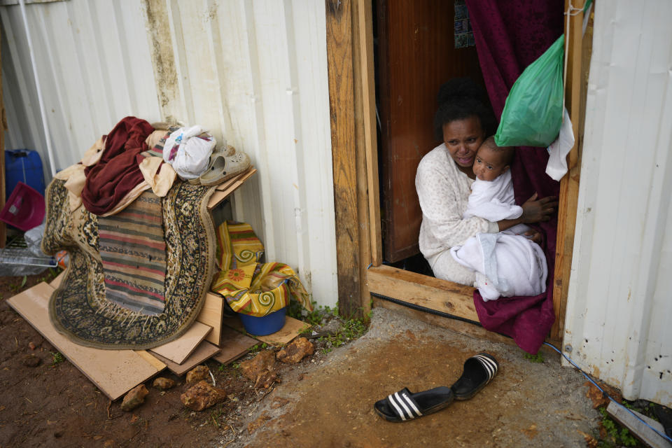 FILE Daisy cries holding her baby by the door of her makeshift house as municipal workers start to demolish her neighboor's house in Loures, outside Lisbon, Monday, March 6, 2023. Daisy and six other families, mostly immigrants from Sao Tome & Principe, were evicted and had their illegal houses demolished. They had built their houses in the last couple of years when unable to pay the rising rents being asked. (AP Photo/Armando Franca, File)