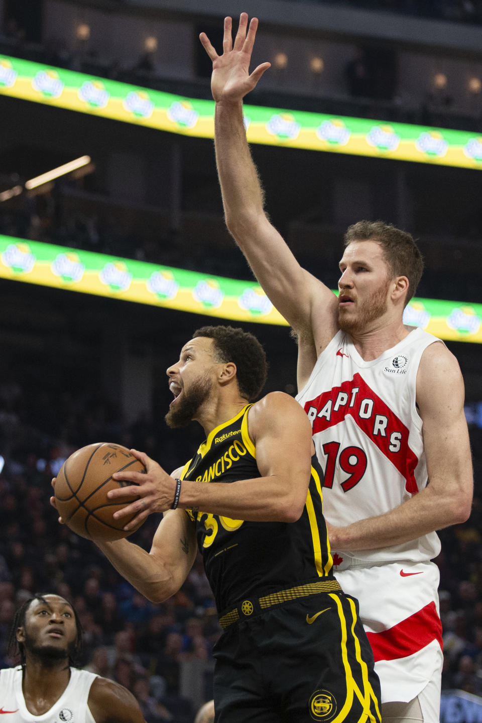 Golden State Warriors guard Stephen Curry (30) drives for a layup under Toronto Raptors center Jakob Poeltl (19) during the first quarter of an NBA basketball game, Sunday, Jan. 7, 2024, in San Francisco. (AP Photo/D. Ross Cameron)