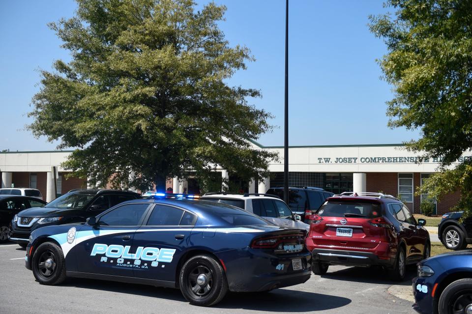 Police cars sit outside T.W. Josey High School after a shooting threat on Tuesday, Sept. 20, 2022. 