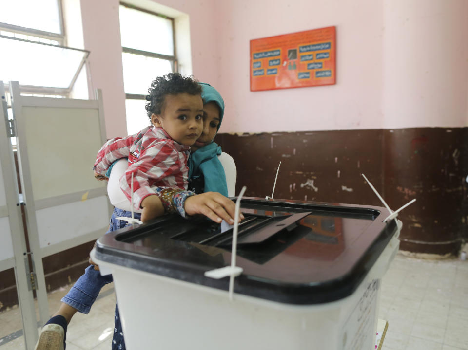 A voters carries her son as she casts her ballot on constitutional amendments during the first day of three-day voting at polling station in Cairo, Egypt, Saturday, April 20, 2019. Egyptians are voting on constitutional amendments that would allow el-Sissi to stay in power until 2030. (AP Photo/Amr Nabil)