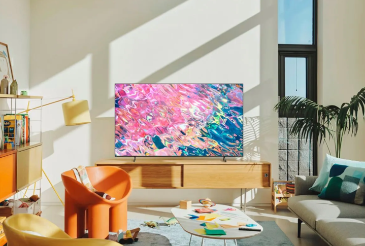 The Samsung Q60B QLED Smart TV sits on a media cabinet in a living room.