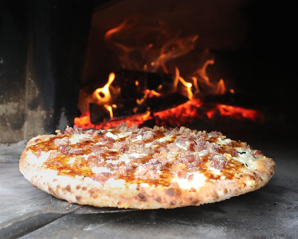 A fig and goat cheese pizza is pulled from an 800 degree wood fired oven at Green Valley Brewing Company on Wednesday.