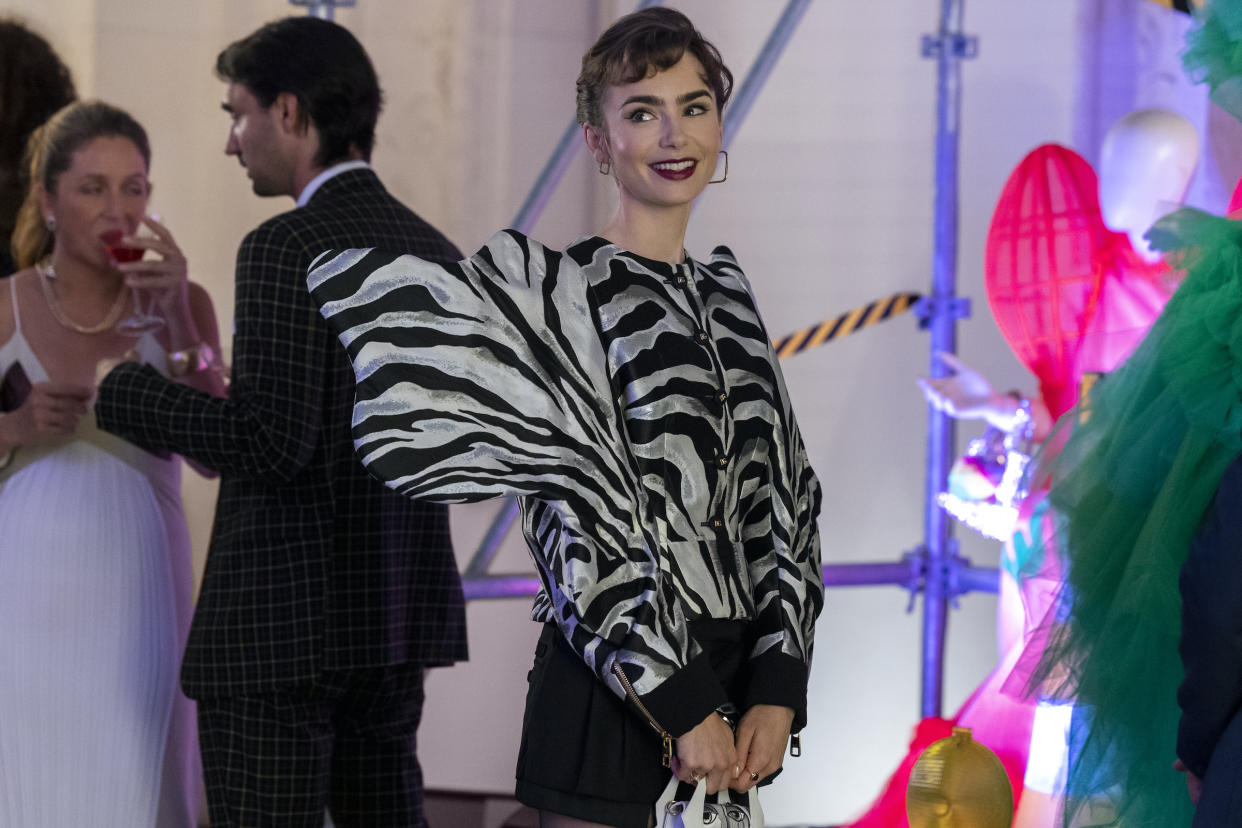 Lily Collins wears a silver and white zebra-striped blouse with a huge, puffy "wing."