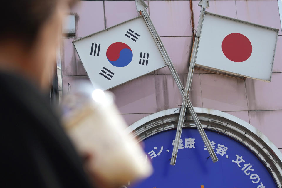 A woman walks past an advertisement featuring Japanese and South Korean flags at a shop in Shin Okubo area in Tokyo Friday, Aug. 2, 2019. Japan has approved the removal of South Korea from a "whitelist" of countries with preferential trade status, escalating tensions between the neighbors. The decision will fuel antagonism between the two neighbors already at a boiling point over the export controls and the issue of compensation for wartime Korean laborers. (AP Photo/Eugene Hoshiko)