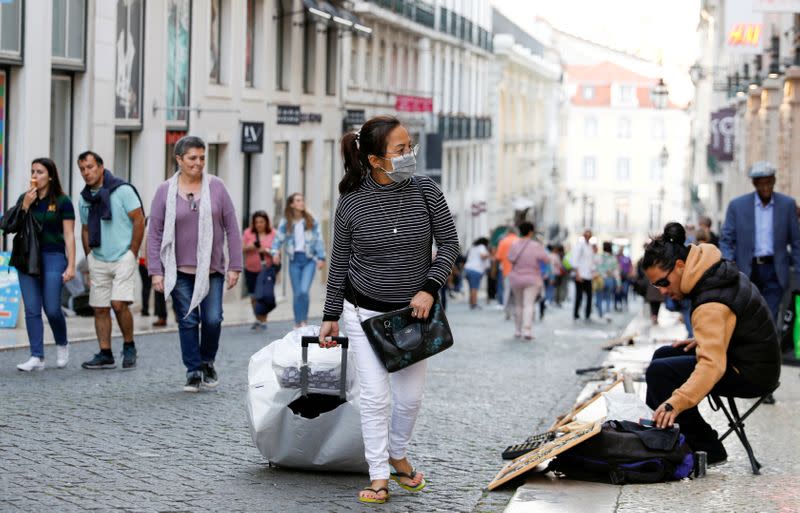 FILE PHOTO: A tourist wearing a protective face mask, due to the coronavirus outbreak, walks in downtown Lisbon