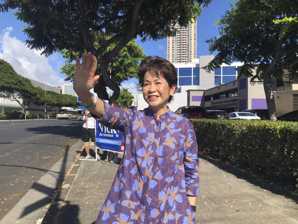 Vicky Cayetano waves at passing cars while campaigning in Honolulu on Aug. 2, 2022. The candidates running in Hawaii's primary election to succeed term-limited Democratic Gov. David Ige include a former first lady, a retired mixed martial arts champion and a congressman who moonlights as a Hawaiian Airlines pilot. (AP Photo/Audrey McAvoy)