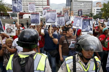 Supporters of Venezuela's President Nicolas Maduro, holding photographs of victims of violence during the protests against Nicolas Maduro's government in 2014, shout next to Venezuelan policemen outside the courthouse during trial of opposition leader Leopoldo Lopez in Caracas September 10, 2015. REUTERS/Carlos Garcia Rawlins