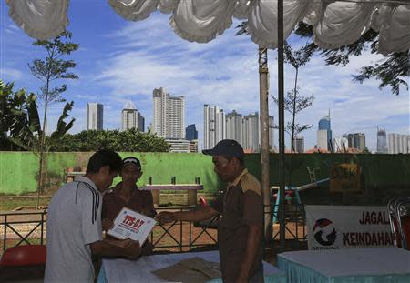 Men hold a sign showing the polling station's number, as the station is prepared for the upcoming parliamentary election in Jakarta April 8, 2014. REUTERS/Beawiharta