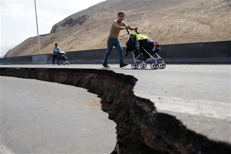 Residents push prams along a damaged road leading to Alto Hospicio commune after a series of aftershocks in the northern port of Iquique April 3, 2014. REUTERS/Ivan Alvarado