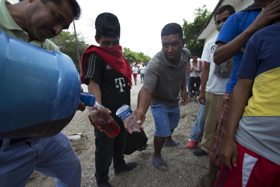 Central Americans fill their water bottles with juice while waiting in line to receive donated food, in Niltepec, Oaxaca state, Mexico, where the migrants stopped for the night, Monday, Oct. 29, 2018. As the caravan resumed its slow advance Monday, still at least 1000 miles or farther from the U.S., the Pentagon announced it would send 5,200 active-duty troops to "harden" the border. (AP Photo/Rebecca Blackwell)