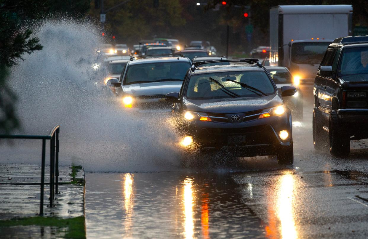 Drivers navigate a lane filled with rain water in Eugene as an atmospheric river moves through the Willamette Valley.