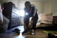 Steven Hamilton sits on his bed in his newly acquired apartment as he puts on sneakers before going for a walk, Wednesday, Sept. 28, 2022, in Boston. Hamilton was homeless for over three years before moving into the apartment in September 2022. (AP Photo/Steven Senne)