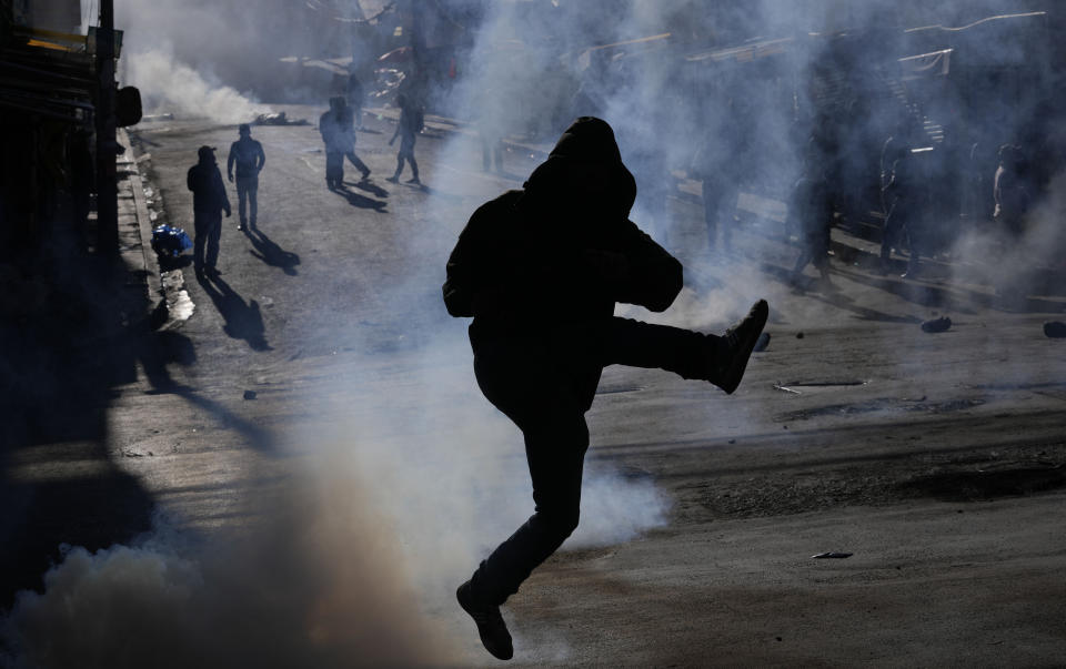 A coca farmer kicks a tear gas canister back a police on the third day of clashes near a coca market in La Paz, Bolivia, Wednesday, Aug. 3, 2022. Anti-government coca farmers are protesting against a new, parallel coca leaf market. (AP Photo/Juan Karita)