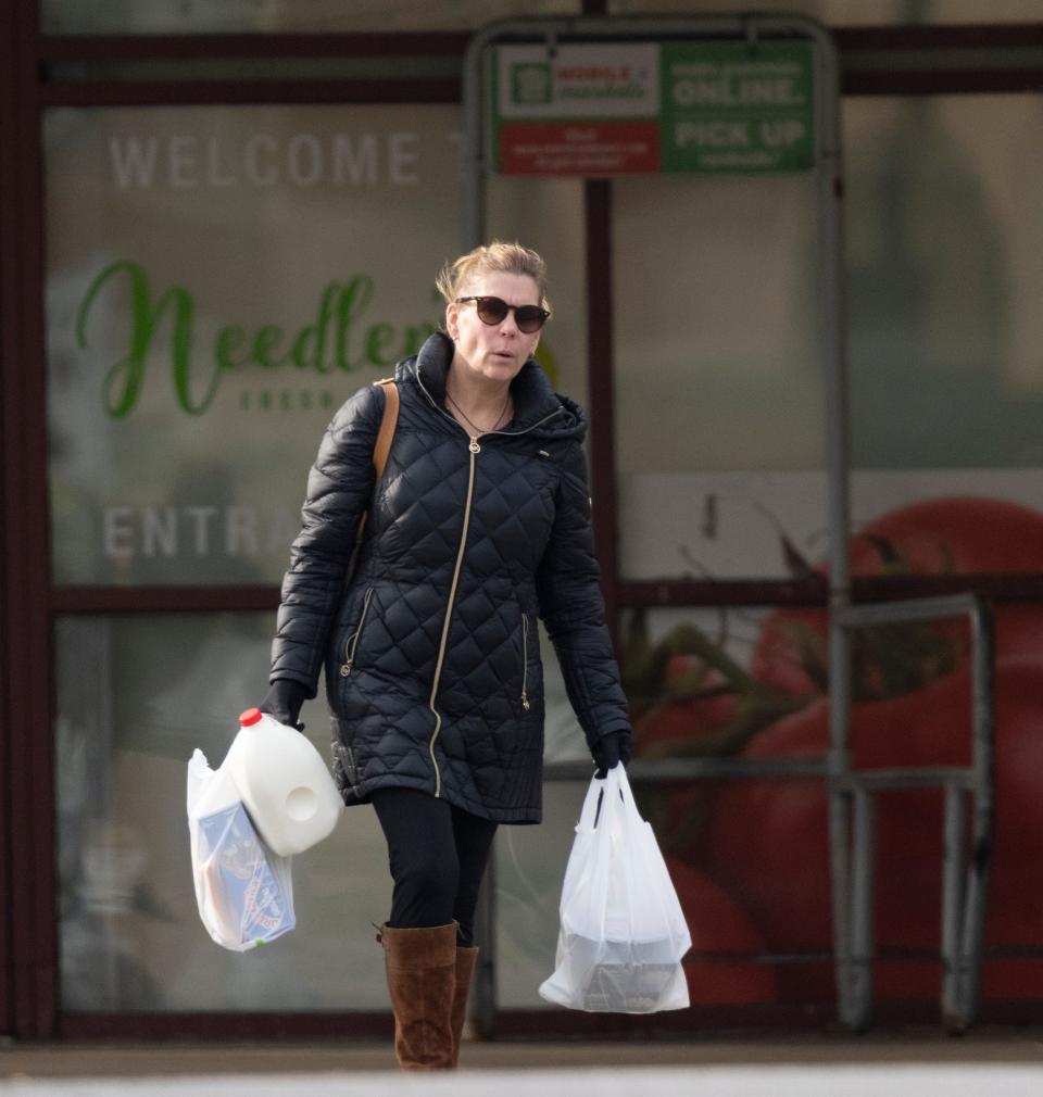 A shopper carries store-provided plastic bags and a gallon of milk away from the Needler’s Fresh Market in downtown Indianapolis on Tuesday, Dec. 13, 2022. On a recent IndyStar survey, 68 percent of the customers at this store used single-use plastic bags, and just over two percent use their own reusable bags. 