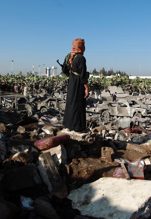 A Yemeni man stands above debris at the site of a Saudi air strike against Huthi rebels near Sanaa Airport on March 26, 2015