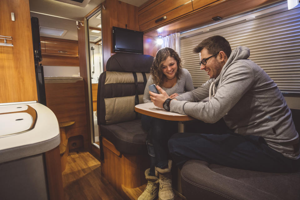 A couple sits inside a contemporary RV.