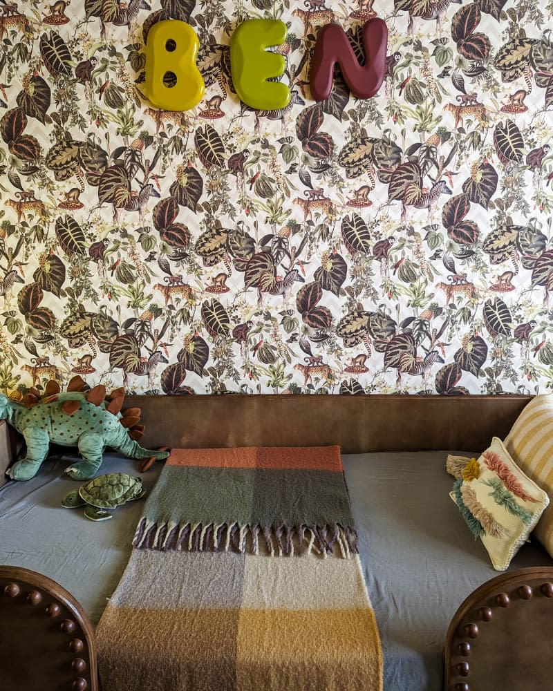 kids room with botanical wallpaper accent wall and brown leather and wood bed