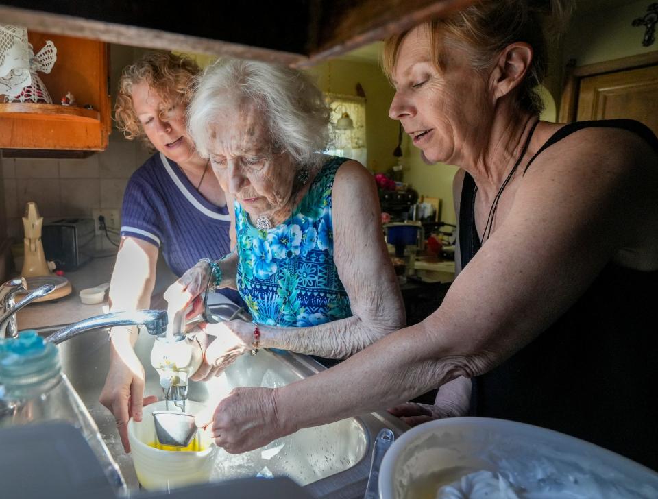 Kristine McCardle, Arlene McCardle and Marybeth McCardle mix cake batter in the sink to contain splatters. The women were marking Arlene McCardle's 90th birthday by making the cake that brought her a measure of fame 70 years ago.