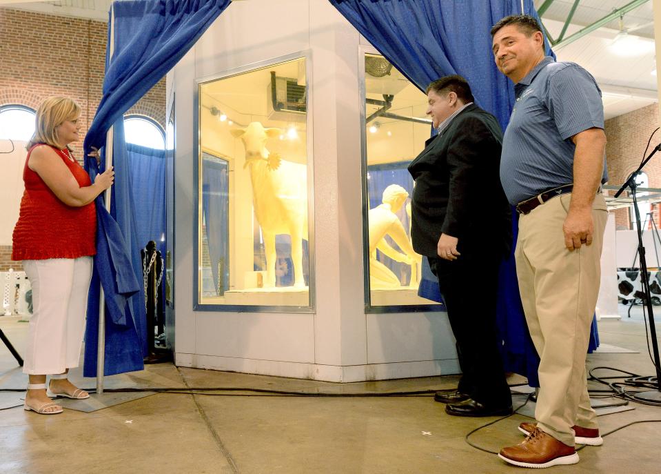Illinois Gov. JB Pritzker and his wife MK open the curtains to reveal this years Butter Cow at the Illinois State Fair after being introduced by the Director of the Illinois Department of Agriculture Jerry Costello, right front,  Wednesday August 10, 2022.