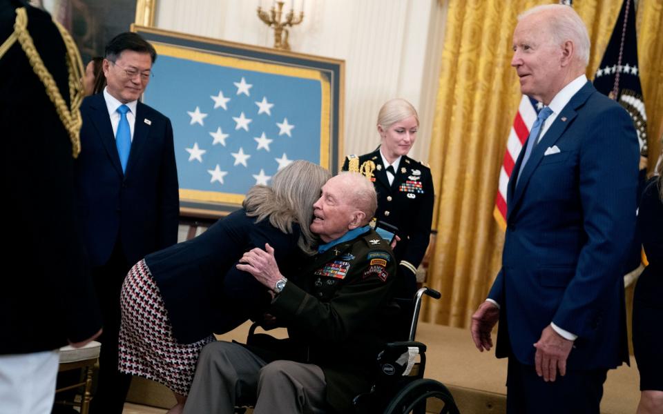 Army Colonel Ralph Puckett is hugged by Senator Joni Ernst as President Biden looks on - Shutterstock
