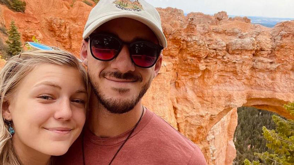 Gabby Petito and Brian Laundrie pose for a selfie in front of canyonland scenery.