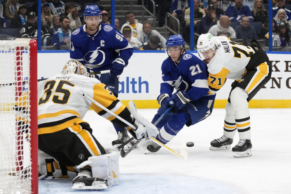 Pittsburgh Penguins goaltender Tristan Jarry (35) makes a save on a shot by Tampa Bay Lightning center Brayden Point (21) during the second period of an NHL hockey game Wednesday, Dec. 6, 2023, in Tampa, Fla. Penguins center Evgeni Malkin (71) attempts to tie up Point. (AP Photo/Chris O'Meara)