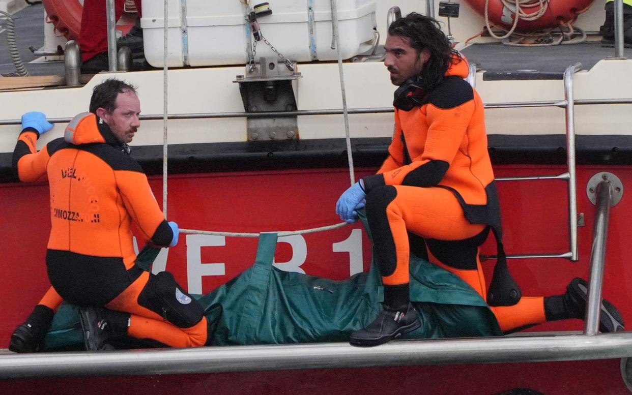 A body bag is brought ashore at the harbour in Porticello on Wednesday